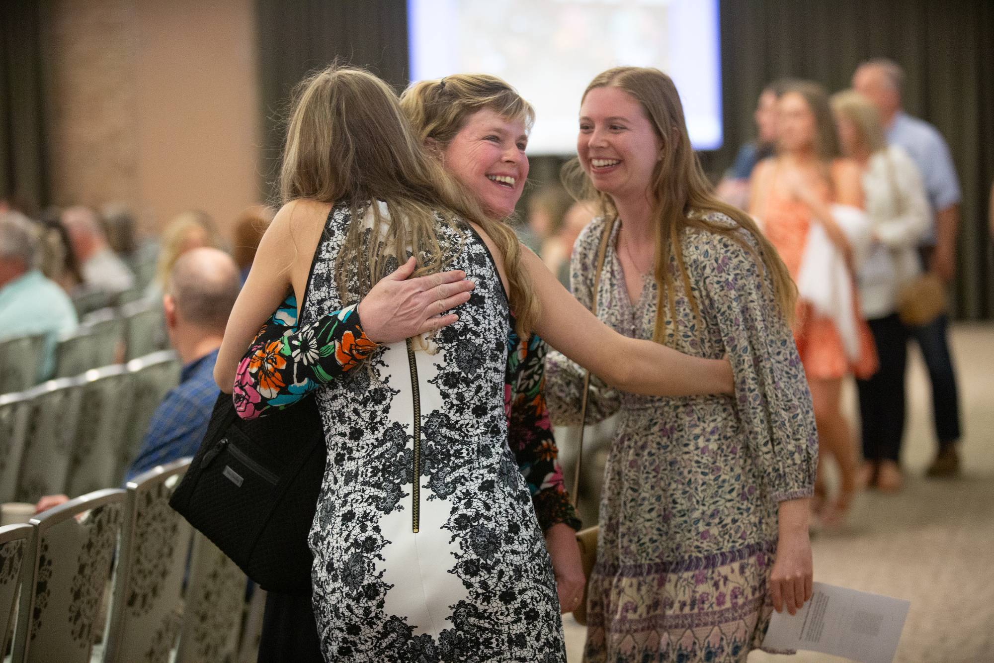 Graduates smiling and hugging family and friends.